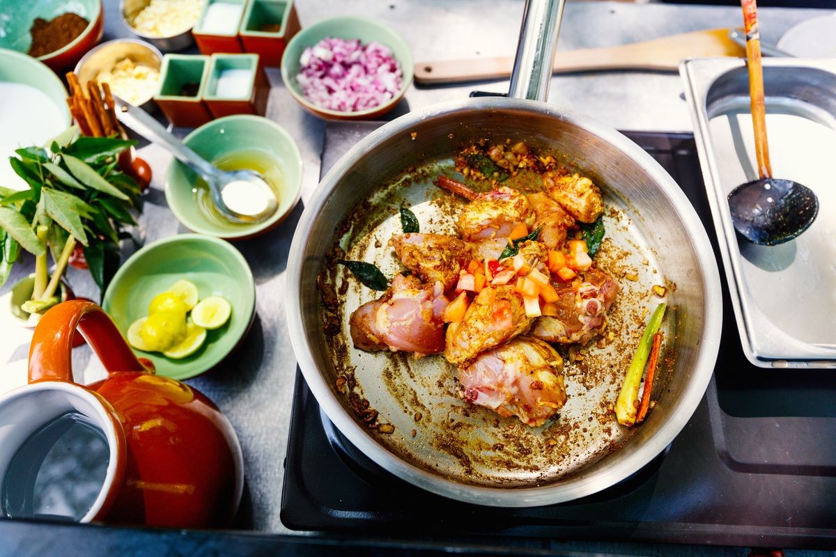 Preparation of traditional Sri Lankan curry dish with tender chicken breast at cooking class